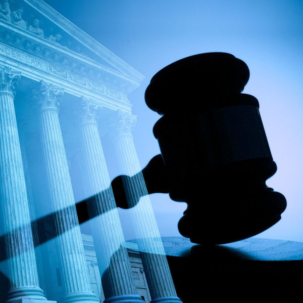 Silhouette of a gavel with court building in background 