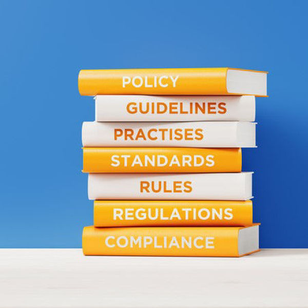 Stacked books with regulatory-related titles, such as Compliance and Guidelines