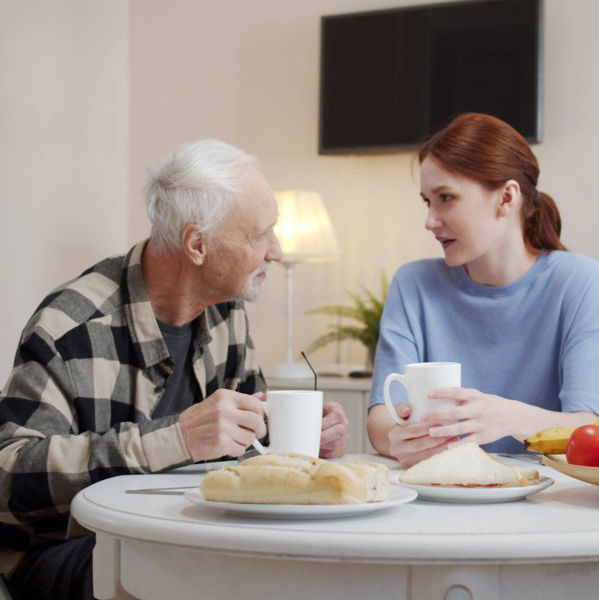Elderly man talking with young woman at dinner table