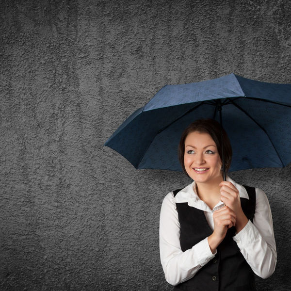 Young business woman standing under an umbrella against a gray background