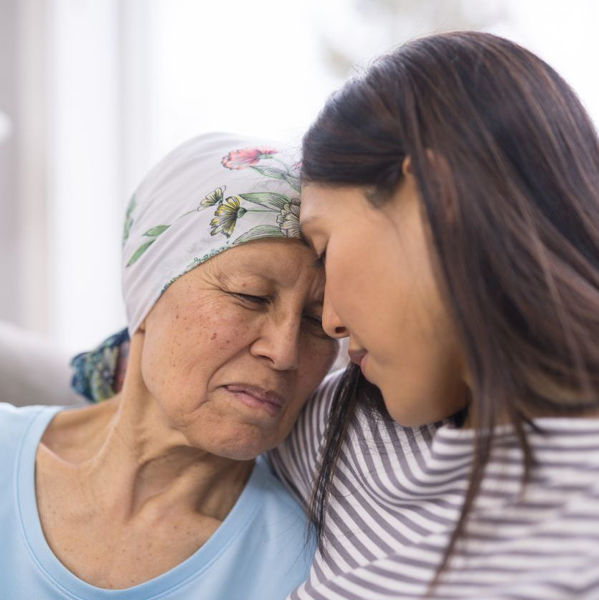 Older female cancer patient being comforted by daughter