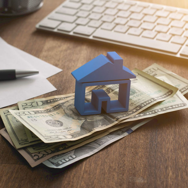 Small model of house sitting on pile of cash