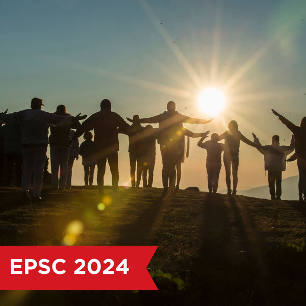 A group of people raising their arms, silhouetted against the rising sun
