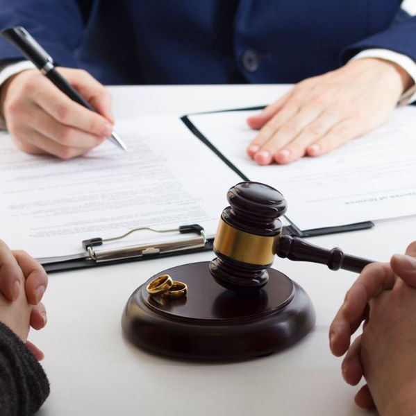Gavel with two wedding rings sitting between lawyer and couple