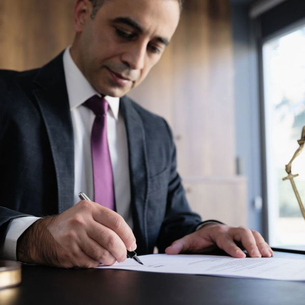 Man in suit sits and desk and signs document
