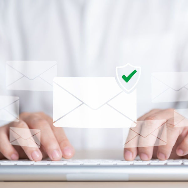 close up of a gentleman typing on a keyboard, overlaid by an envelope image with a green check mark