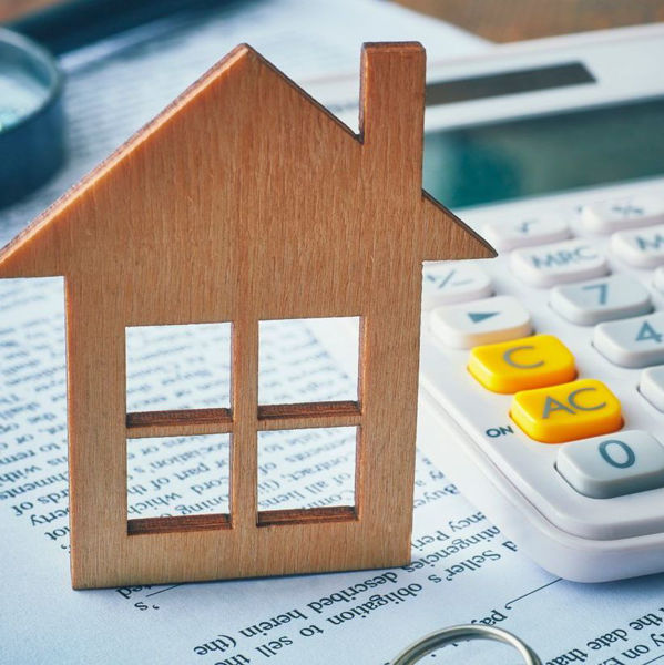 Wooden cutout of a house standing next to a calculator